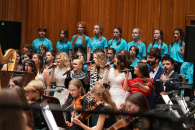 wokaliści i chór dziecięcy śpiewający do mikrofonów