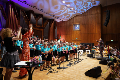 chór dziecięcy, orkiestra i dyrygent cieszący się na estradzie