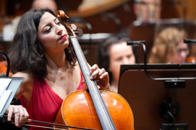 kobieta w czarnych włosach i czerwonej sukience grająca na wiolonczeli