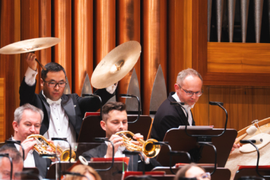 dwoje mężczyzn w średnim wieku, jeden uderzający w czynele, a drugi w wielki bębęn