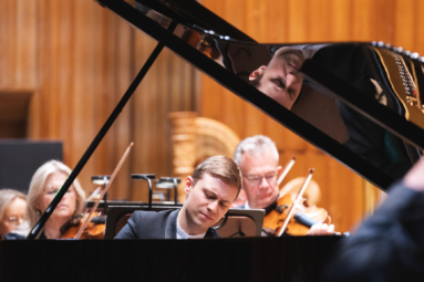 młody pianista skupiony na grze na fortepianie