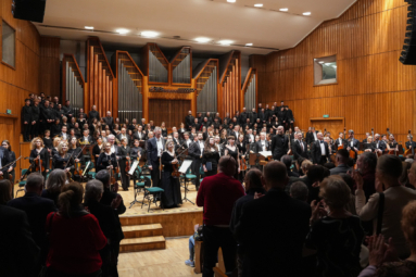 zdjęcie orkeistr, chóry, solistów i dyrygenta zwróconych w stronę publiczności