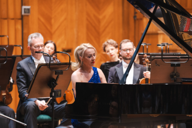 zdjęcie pianistki w cekinowej niebieskiej sukience skupionej na grze na fortepian