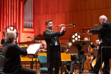 zdjęcie mężczyzny grającego na podłużnej trąbce i stojącego obok niego dyrygenta