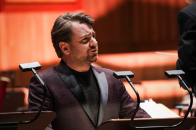 mężczyzna w bordowej marynarce od smokingu śpiewający solo