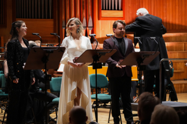 śpiewacy w wieczorowych strojach śpiewający do siebie