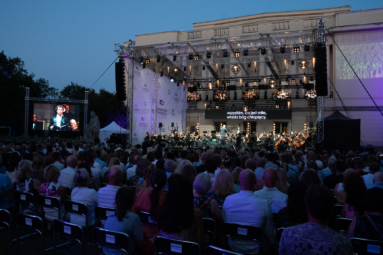 Plenerowy koncert orkiestry i chóru przed gmachem FP, z licznie zgromadzoną publicznością i wieczorną atmosferą