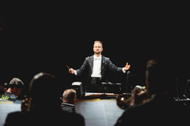 dyrygent widziany od prozodu w skupieniu yrygujący orkiestrą