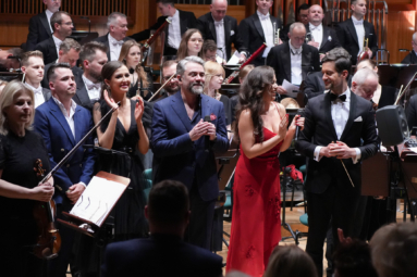 wokaliści w wieczorowych strojach uśmiechający się do publiczności