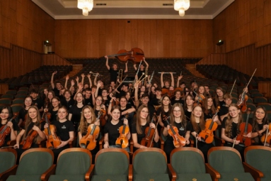 zdjęcie młodzieży z orchestra4young siedzącej na publiczności i w rękach trzymającej instrumenty