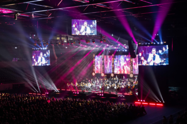 zdjęcie estrady oświetlonej kolorowymi światłami, na której siedzi orkiestra symfoniczna FP