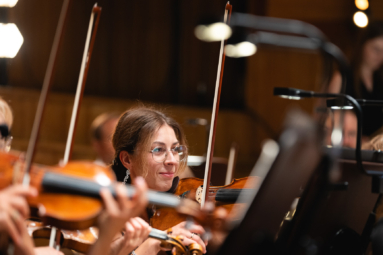 zdjęcie skrzypaczki w okularach z uśmiechem na twarzy grającej na instrumencie