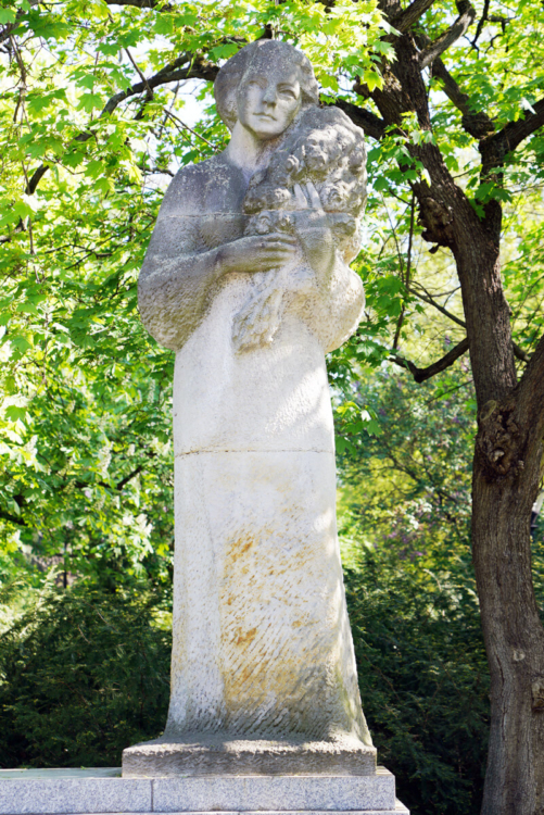 Rzeźba wykonana z piaskowca przedstawia sylwetkę Grażyny Bacewicz z realistycznymi rysami twarzy i detalami.