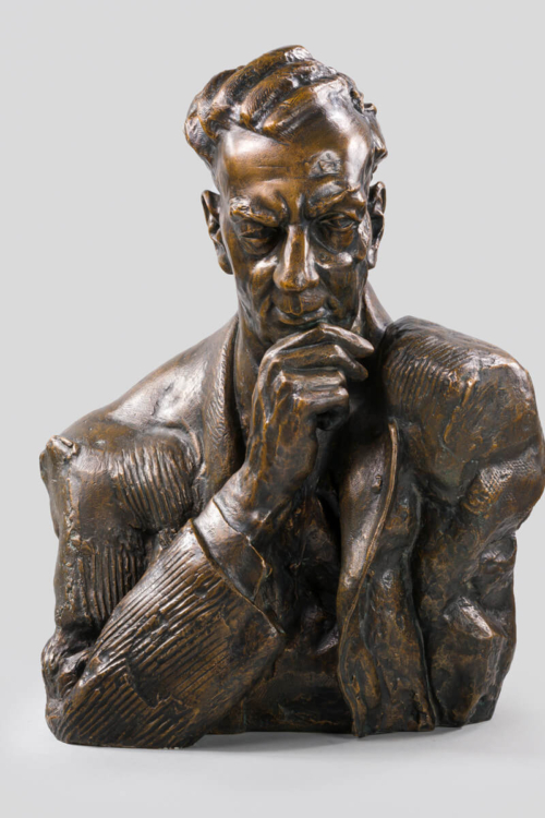 Popiersie wykonane z brązu przedstawia Benjamina Brittena z realistycznymi rysami twarzy i detalami.